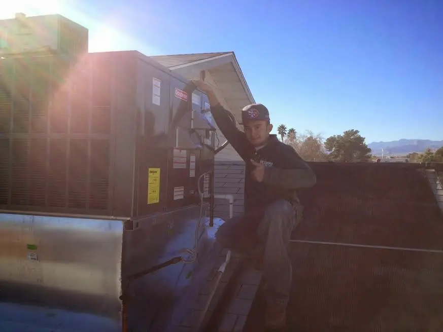HVAC technician performing AC Tune-Up on a rooftop unit in Pompey